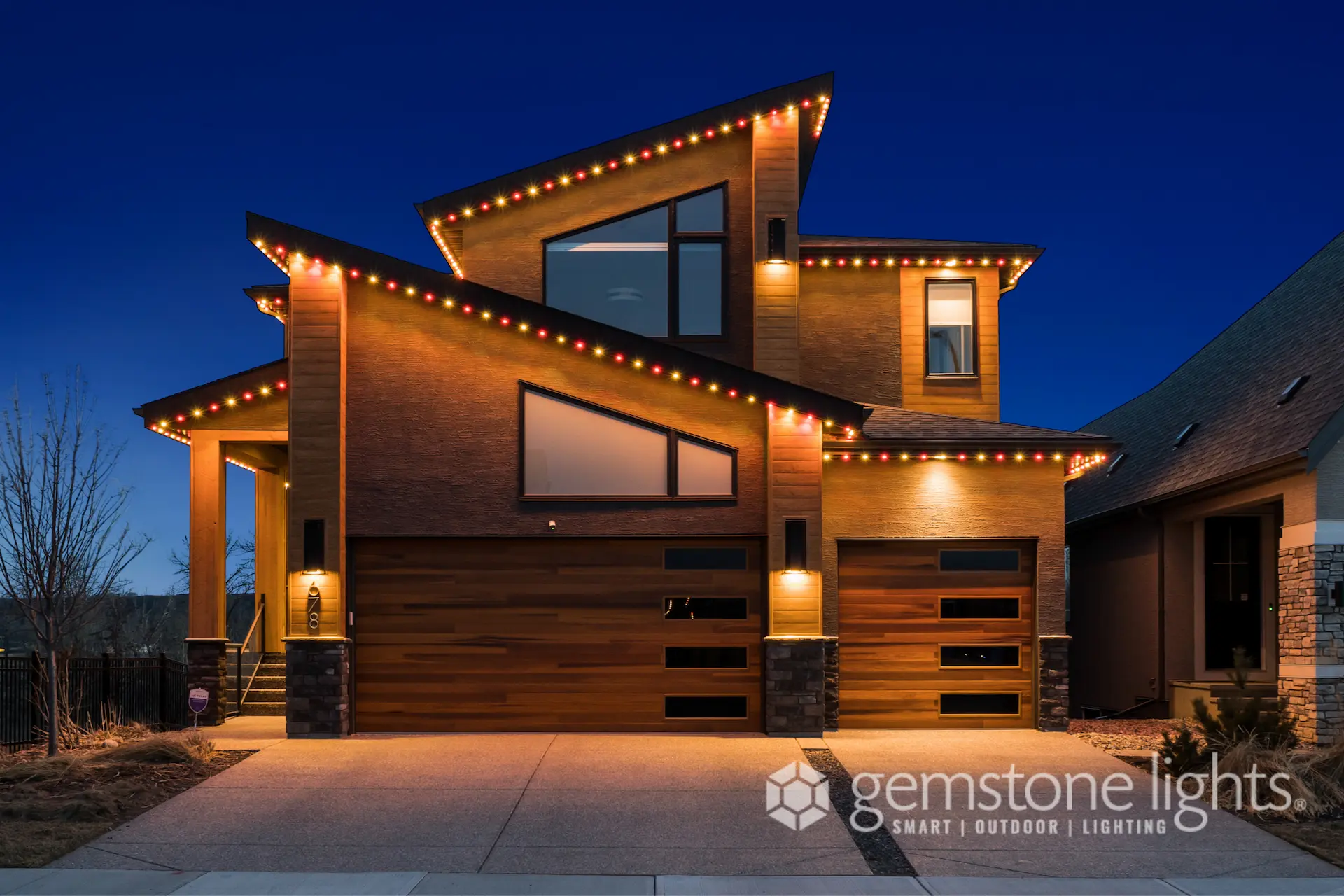A modern house is illuminated with decorative lights against a twilight sky