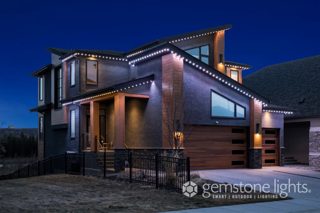 A modern house is illuminated by decorative lights against a twilight sky