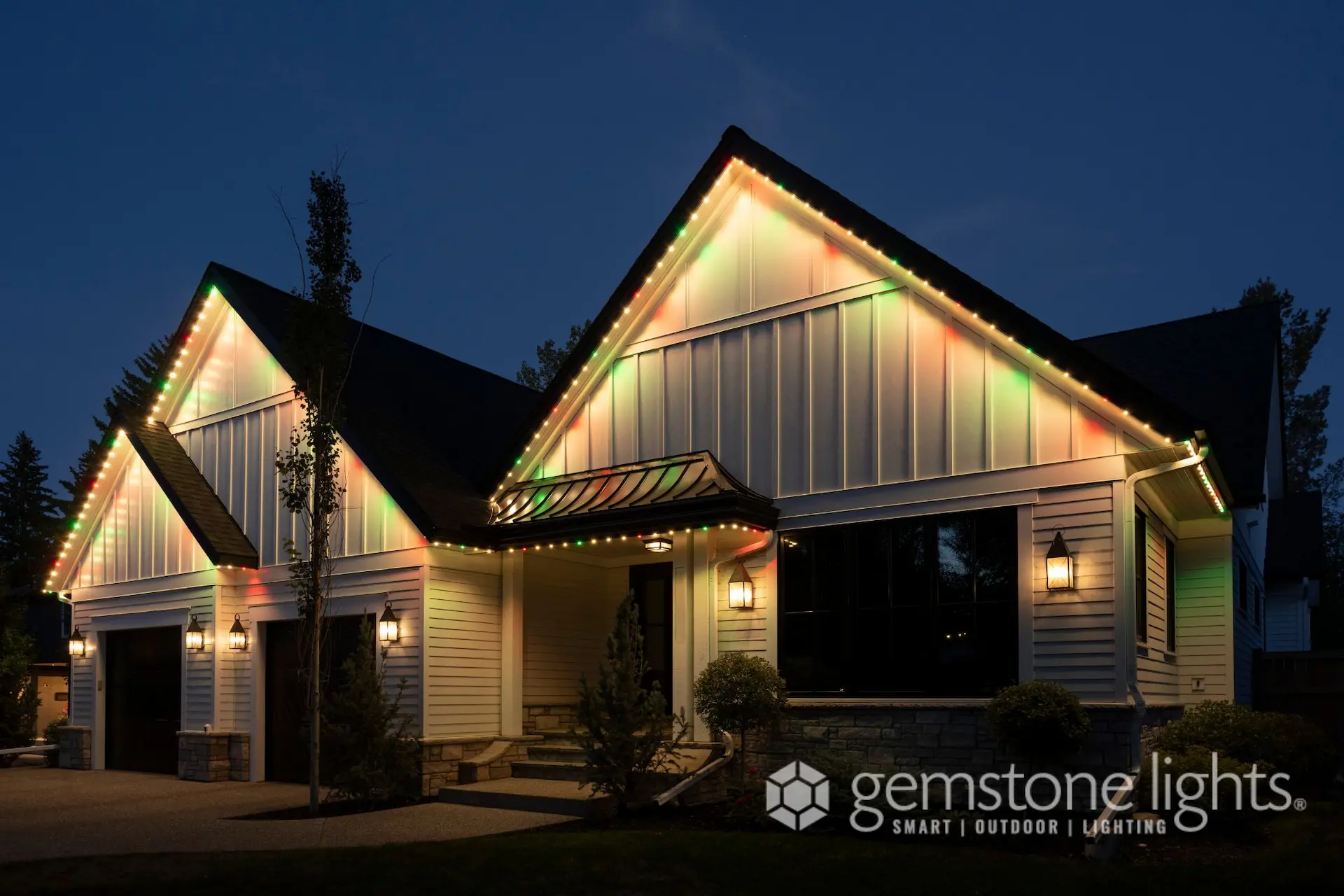 A house is illuminated with colorful lights along its roofline at dusk