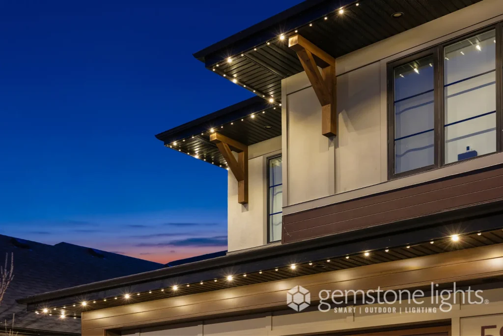 Warm outdoor lights illuminate the architectural features of a modern home at dusk