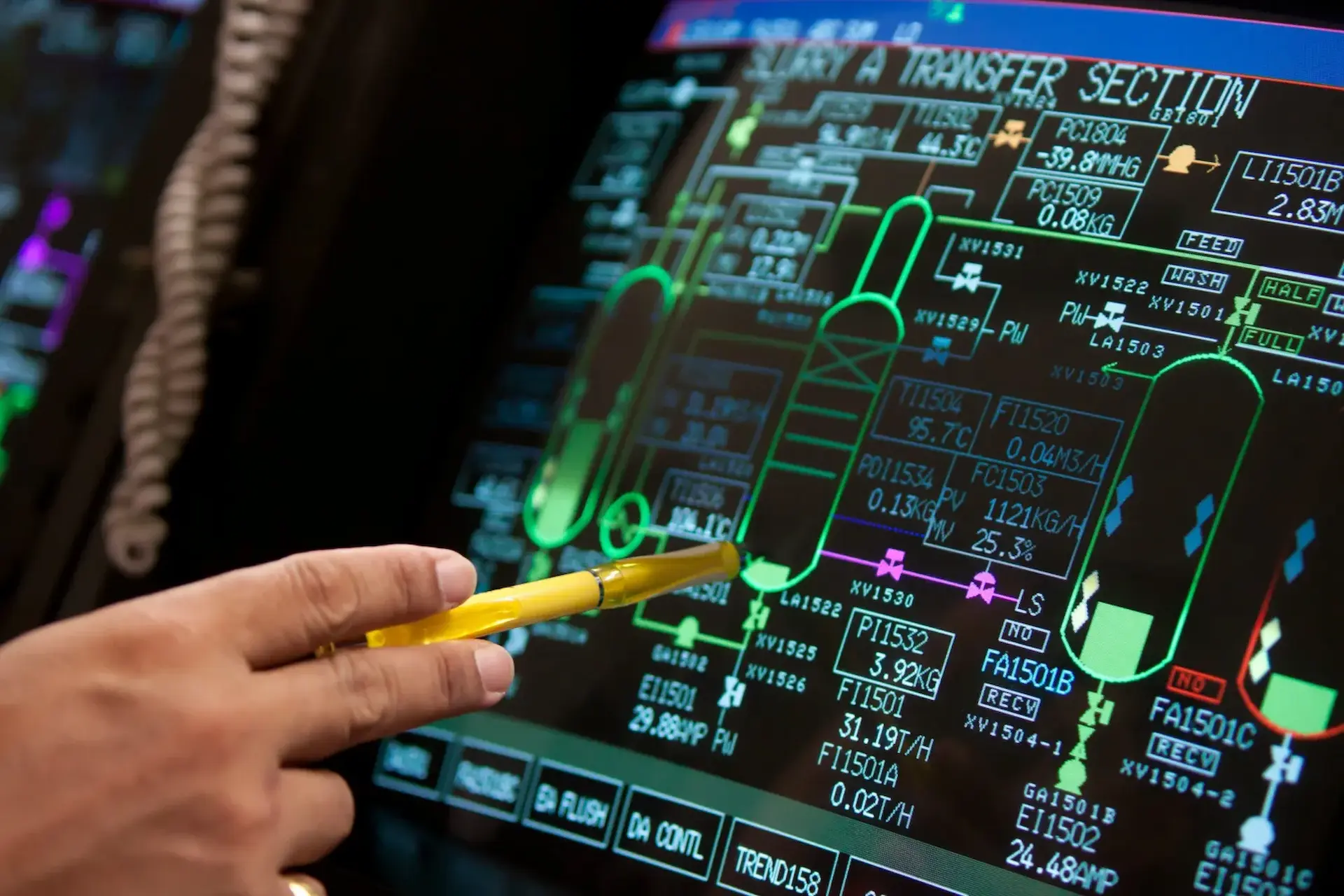 A hand gestures towards a colorful, complex digital control interface displaying various data points