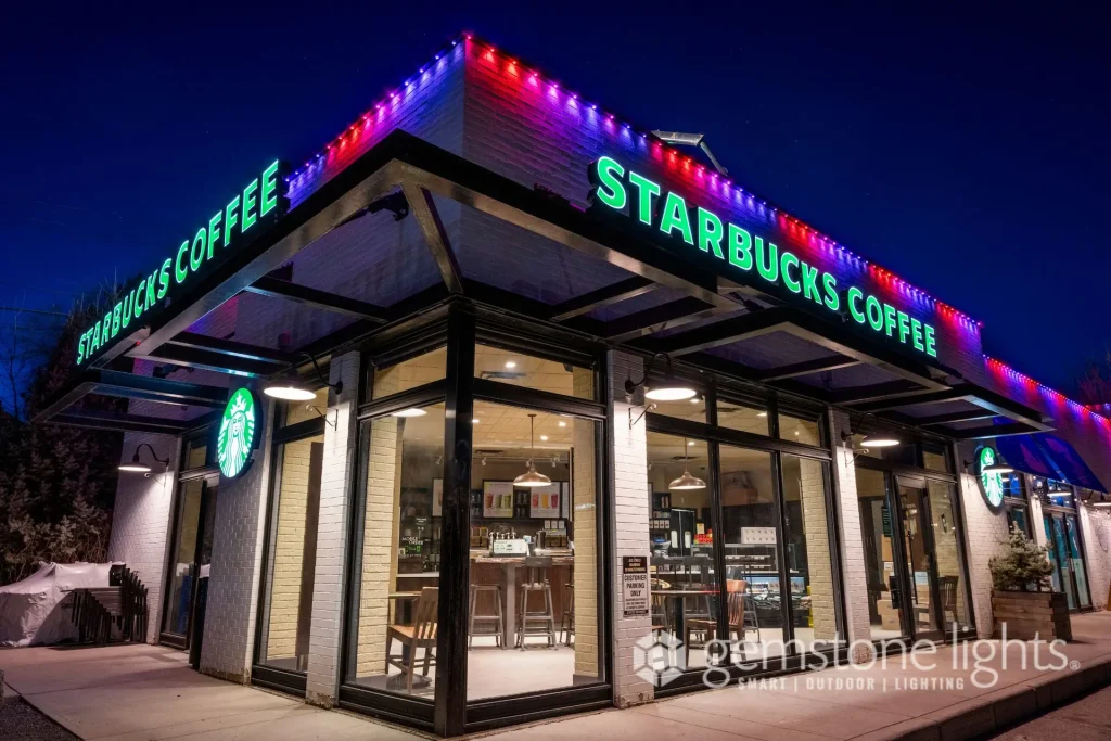 Brightly lit coffee shop features a prominent green sign and colorful lights at dusk