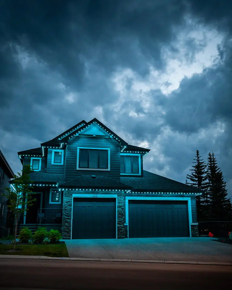 A modern home is adorned with blue lights under a moody, overcast sky