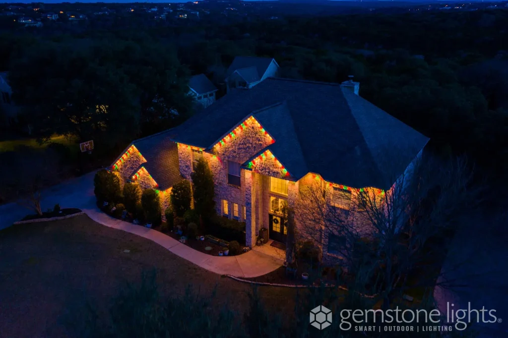 A beautifully lit stone house surrounded by greenery at dusk