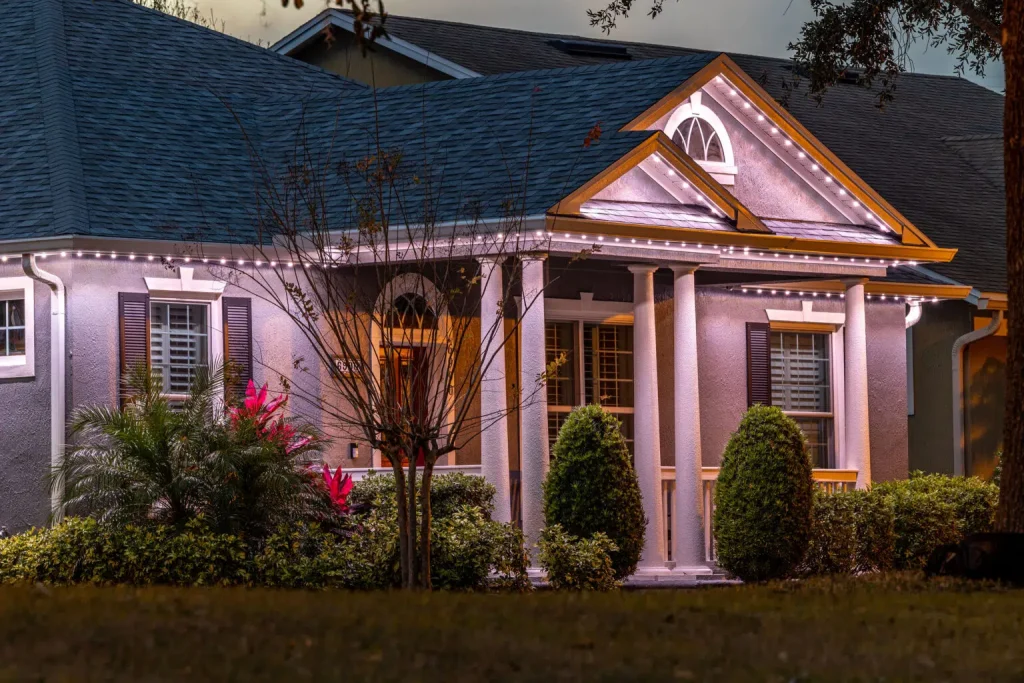 A well-lit house with a welcoming porch surrounded by lush greenery
