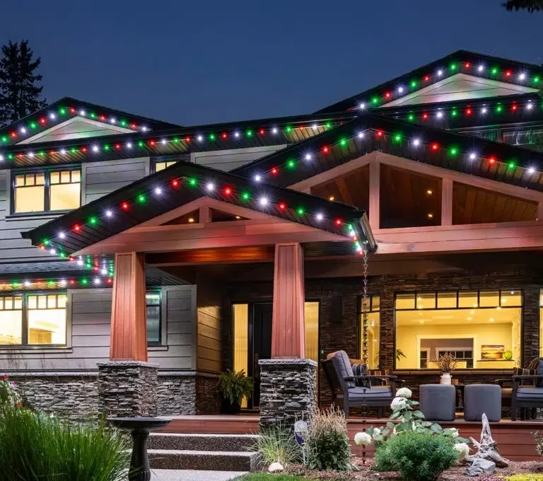 A beautifully decorated house glows with colorful holiday lights at dusk