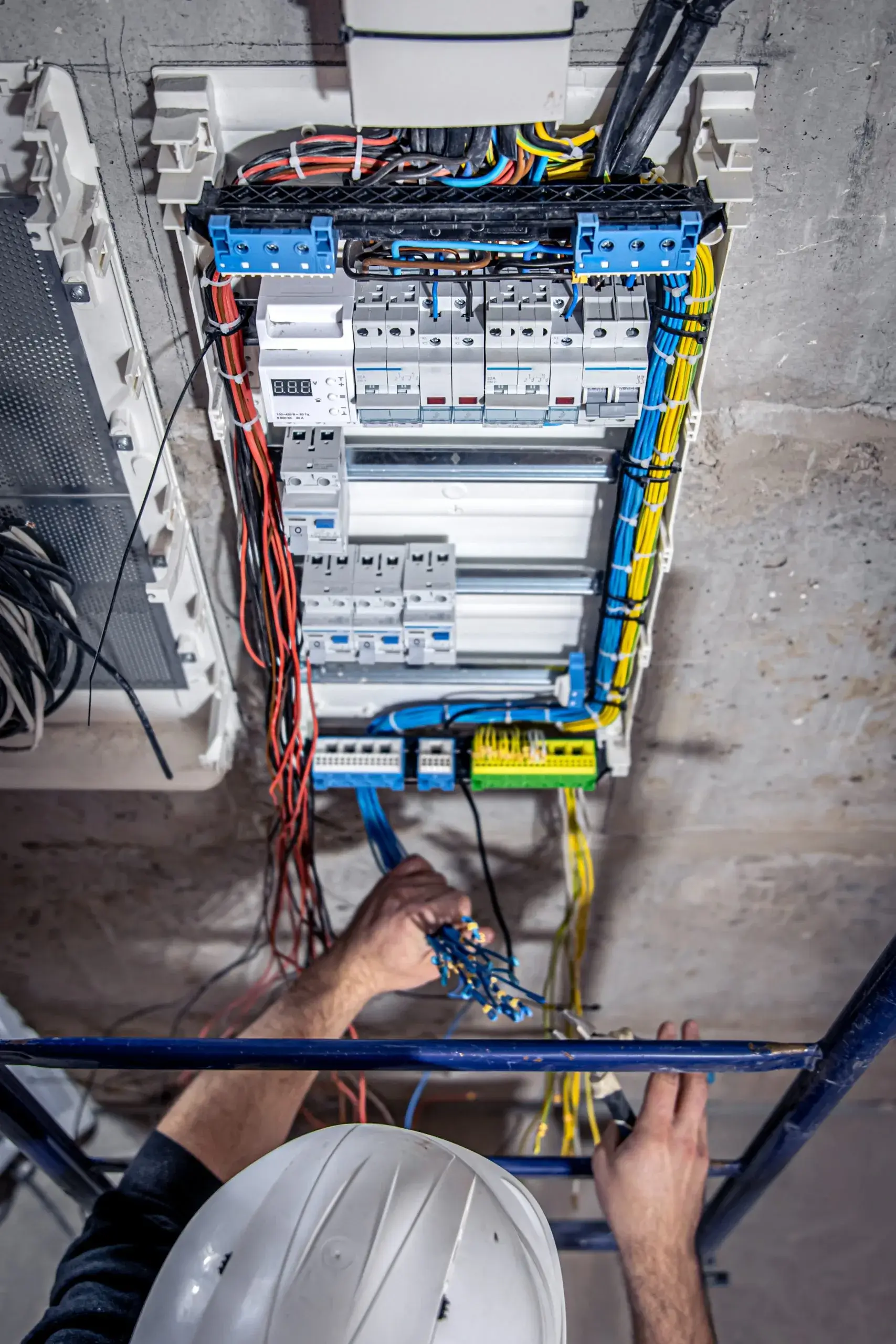 A technician is working on a complex array of electrical wiring and panels