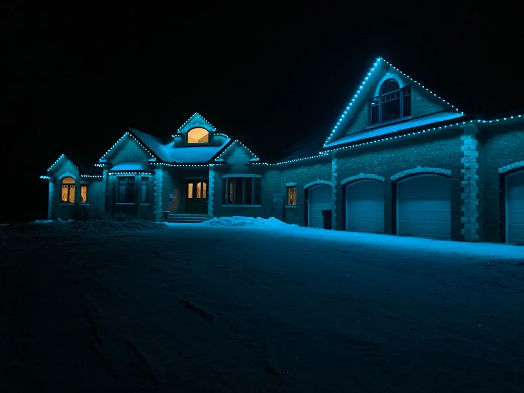 A large house glows with blue lights against a snowy night backdrop